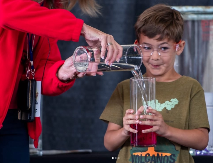 Student watching liquid being poured by staff.